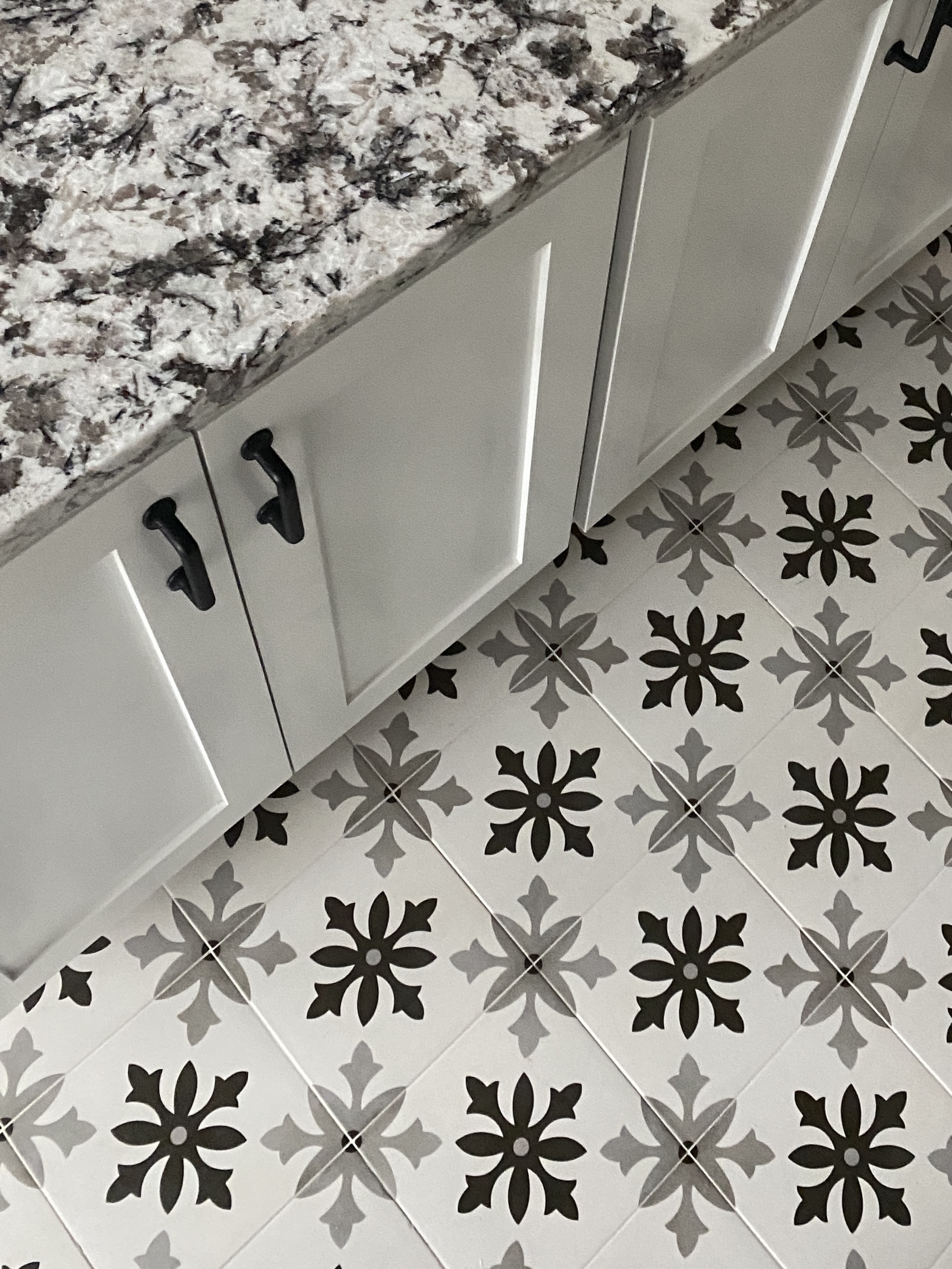 Kitchen island with white marble quartz countertop, black handles, and geometric mosaic floor tile