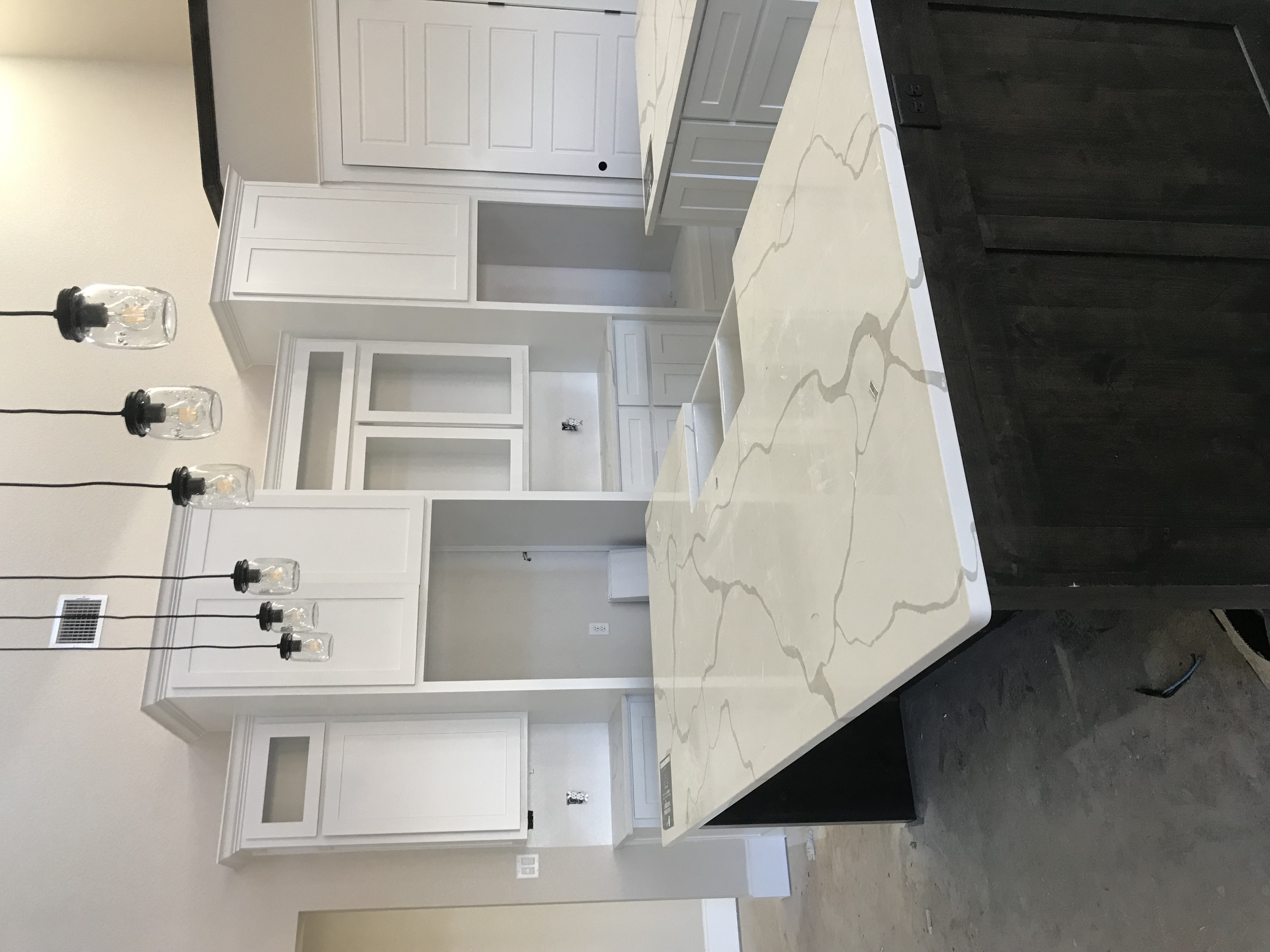 Kitchen island with white marble quartz counter, black base, and modern pendant lighting in Decatur TX