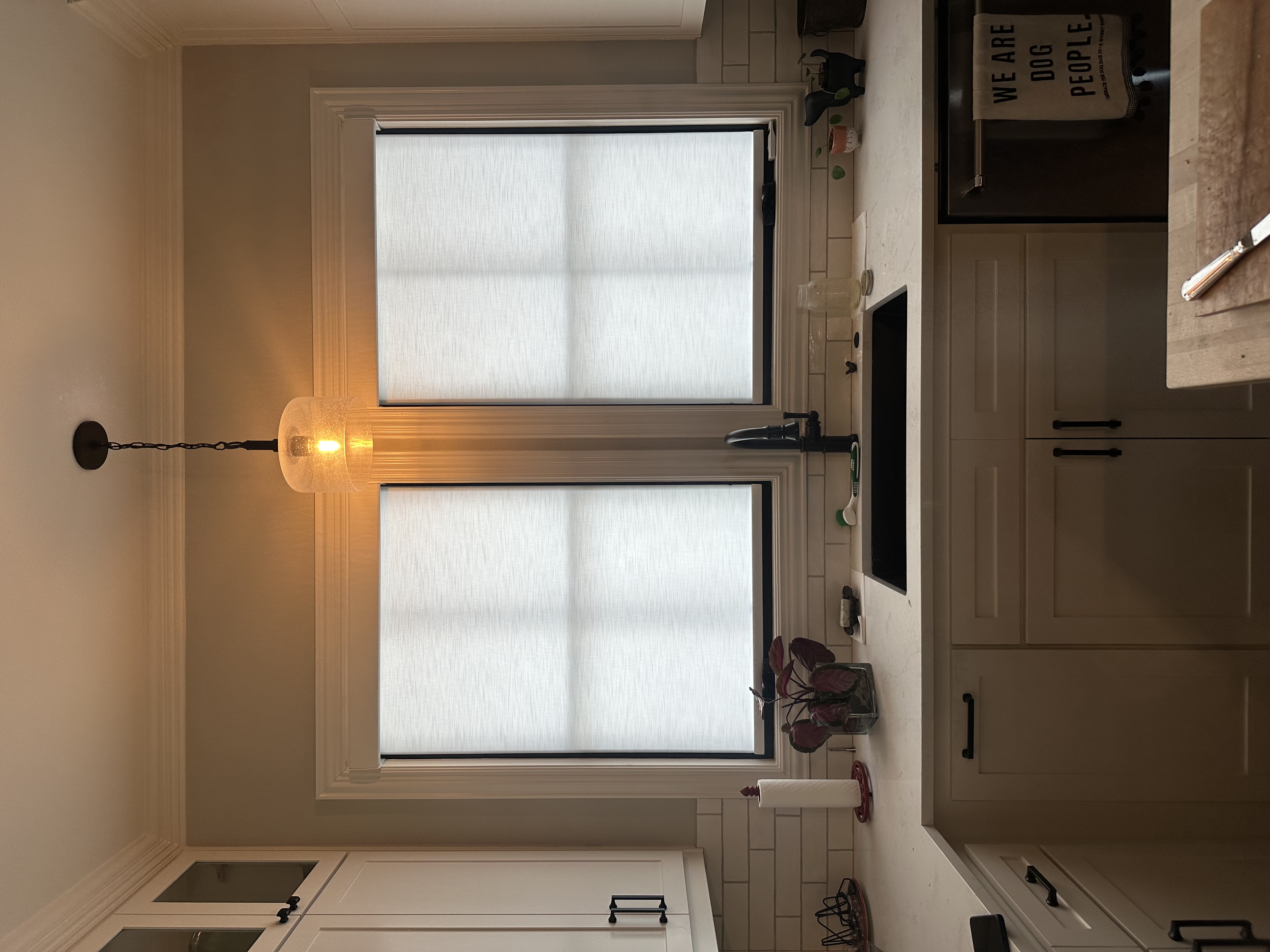 Kitchen window treatment with linen Roman shades over sink with dark frame windows